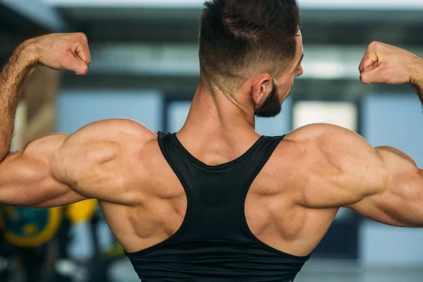 Un giovane atleta si allena in palestra. Mostra i bicipiti — Foto Stock