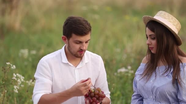 Belo casal homem e mulher grávida comem uvas vermelhas. Comida saudável. Frutas frescas. Sorriso de mulher feliz — Vídeo de Stock