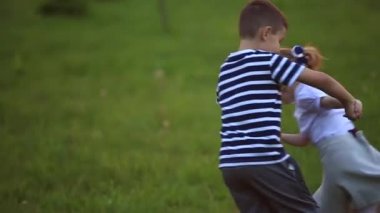 Küçük erkek ve kız çalıştırmak ve yürütmek. Karahindiba patlattılar. günbatımı