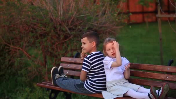 Petit garçon et fille assis sur le banc et mange une glace — Video