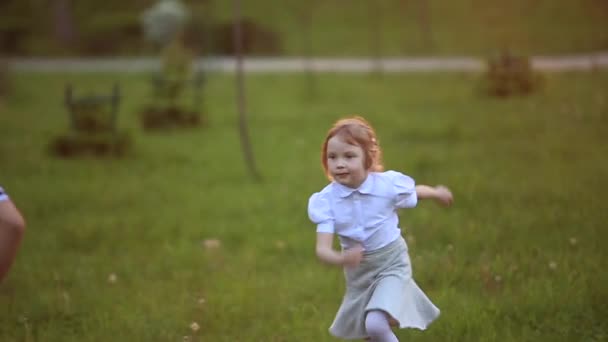 Petit garçon et petite fille courent et jouent. Ils font sauter le pissenlit. coucher de soleil — Video