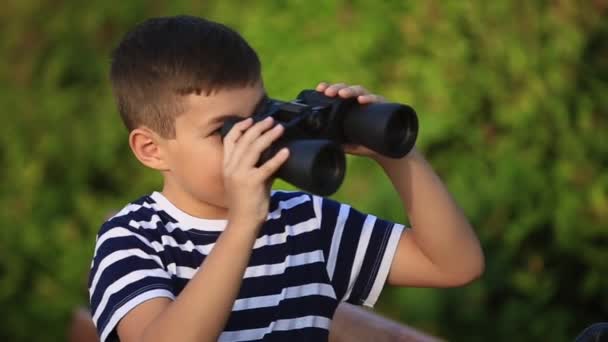 Kleiner Junge spaziert durch den Park und schaut durch Ferngläser — Stockvideo