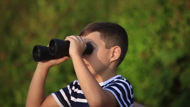 Kleiner Junge spaziert durch den Park und schaut durch Ferngläser — Stockvideo