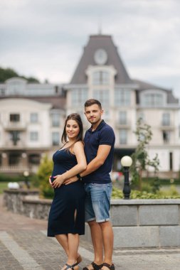 Hamile kadın ve onun husbant birbirleriyle ve gülümseme sarıl. Adam oryantal hamile kadının elini koydu. Altı aylık hamilelik