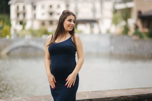 Joven mujer embarazada hermosa de pie cerca del lago —  Fotos de Stock