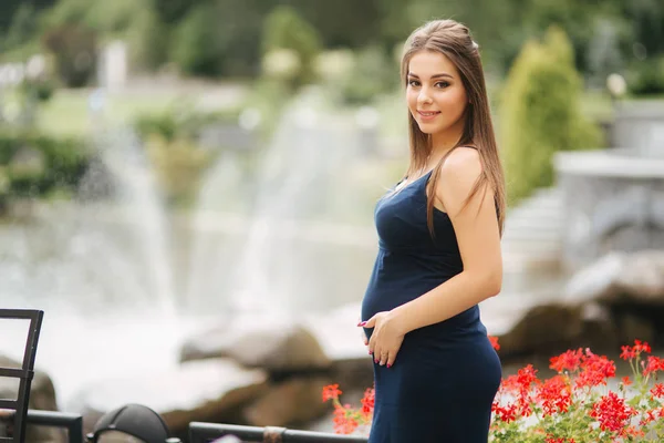 Hermosa mujer embarazada en vestido azul sonrisa. Mujer ternura caminar fuera. Seis meses de embarazo —  Fotos de Stock