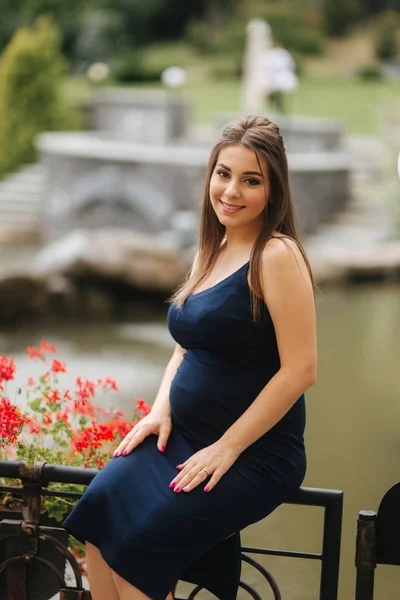 Красива вагітна леді в блакитній сукні посміхається. Ніжна жінка виходить на вулицю. Шість місяців вагітності — стокове фото
