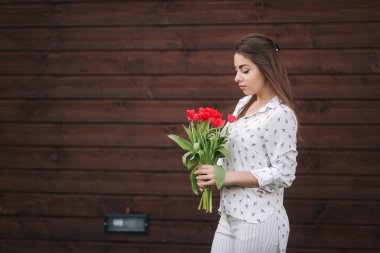Kırmızı çiçekler Buket ile güzel kız evi tarafından hazır. Ahşap arka plan