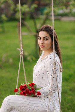 Bayan Beyaz evinin arka bahçesinde salıncakta oturamaz. O bir re tutun çiçekler