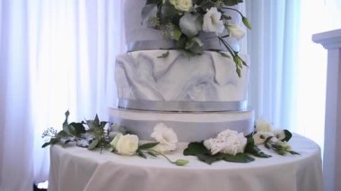 Güzel düğün pastası çiçeklerle süslenmiş. Beyaz ve gümüş renkli kek