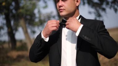 Papyon konumu dışında olan siyah elbiseli damat. Sokakta ağaç. Moda adam