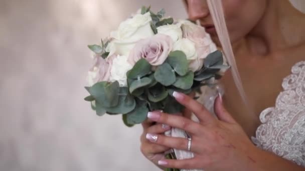 A noiva elegante mantém um buquê de casamento nas mãos. Menina de cabelo loiro bonita com maquiagem de moda e penteado. Modelo feminino no hotel — Vídeo de Stock