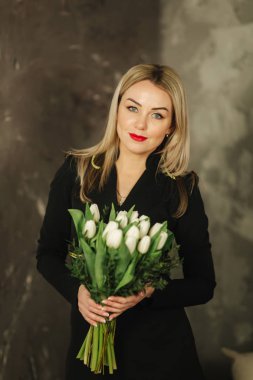 Güzel anne tutun 8 Mart Beyaz Lale bir buket. Kadının el çiçeklenir. Sarı saçlı anne ile evde çiçek