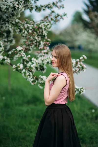 Bella ragazza dai capelli biondi in piedi davanti all'albero in fiore. bella primavera — Foto Stock