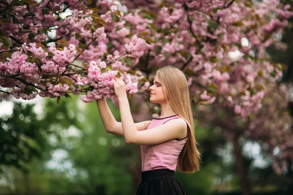 Retrato de hembra europea cerca del árbol floreciente japonés de sakura. Chica rubia del pelo —  Fotos de Stock