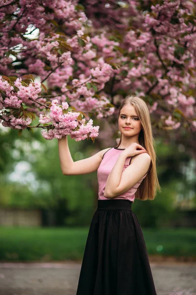 Ritratto di femmina europea vicino all'albero fiorito giapponese di sakura. Ragazza capelli biondi — Foto Stock