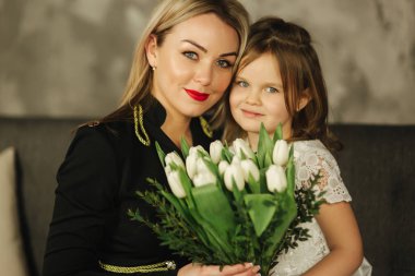 Küçük kızı anne buket çiçek ver. Anne ve kızı evde. Buket çiçek 8 Mart