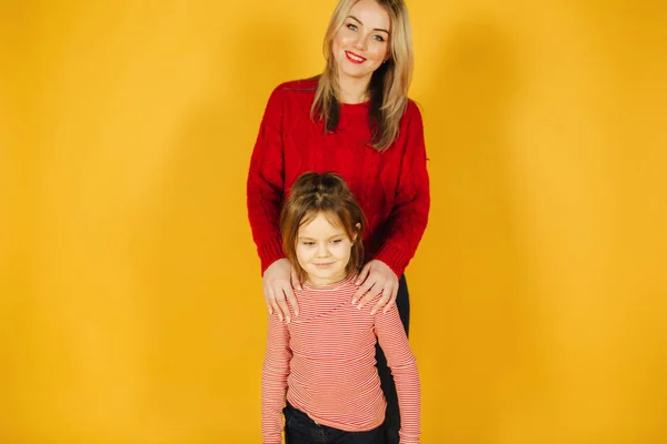Μαμά και κόρη που στέκεται πάνω σε κίτρινο φόντο στο studio — Φωτογραφία Αρχείου