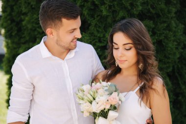 Yakışıklı adam ve Beyaz giysili güzel kızı. Dışında yürüme çift. Buket çiçek