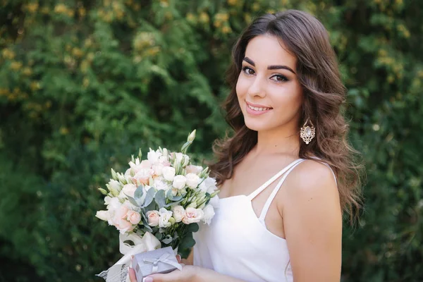 Linda fêmea de vestido branco lodo. Menina bonita segurar um buquê de flores nas mãos — Fotografia de Stock