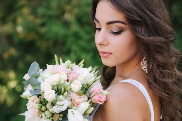 Hinreißende Frau im weißen Kleid Schleim. schönes Mädchen hält einen Blumenstrauß in den Händen — Stockfoto