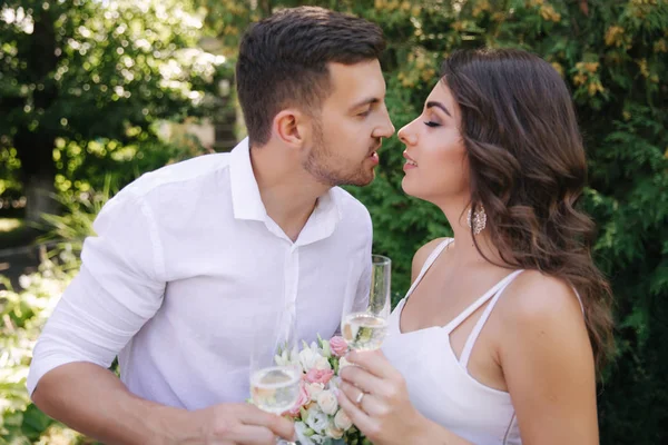 Noiva e noivo a beber champanhe e a beijar. Casal feliz — Fotografia de Stock