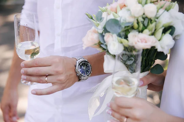 Sposo tenere un bicchiere con champagne. Bouquet di fiori — Foto Stock