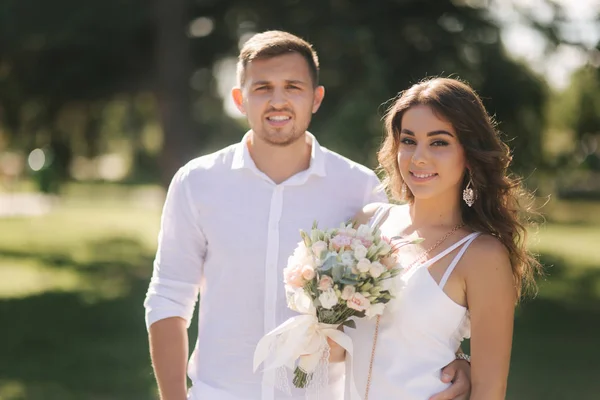 Brudgummen och bruden i deras bröllopsdag promenader i parken. Nygifta tillbringa tid tillsammans. Smekmånaden — Stockfoto