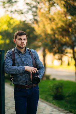 Yakışıklı sakallı adam tutuşsun profesyonel bir fotoğraf. Fotoğrafçı gömlekli kamera için bir deri kayışı kullanın