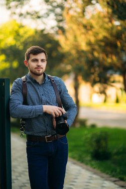 Yakışıklı sakallı adam tutuşsun profesyonel bir fotoğraf. Fotoğrafçı gömlekli kamera için bir deri kayışı kullanın