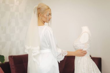 Genç ve güzel gelini evde. Sarı saçlı kız gelinlik