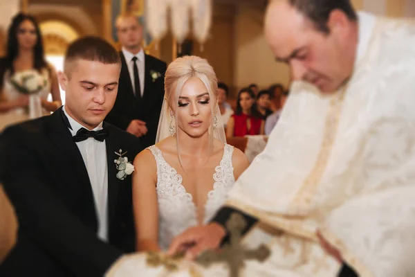 Belo casal na igreja. Os recém-casados juram um ao outro amar para sempre. Noiva feliz e noivo — Fotografia de Stock