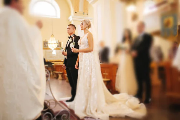 Belo casal na igreja. Os recém-casados juram um ao outro amar para sempre. Noiva feliz e noivo — Fotografia de Stock