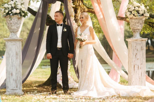 Cerimonia nuziale fuori. Sposo e sposa accanto al grande albero. Decorazione nel parco. Sfondo del lago — Foto Stock