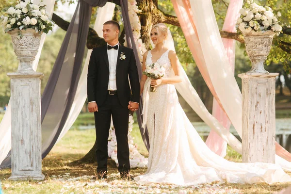 Cerimônia de casamento lá fora. Noivo e noiva ao pé da árvore grande. Decoração no parque. Contexto do lago — Fotografia de Stock