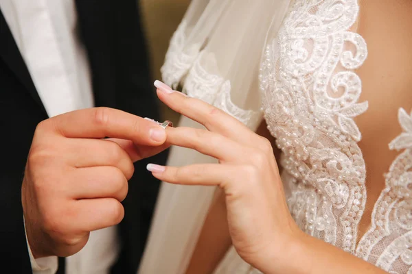 Closeup of hand groom and bride. Groom hold a ring in hands and puts the ring on the brides finger Royalty Free Stock Images