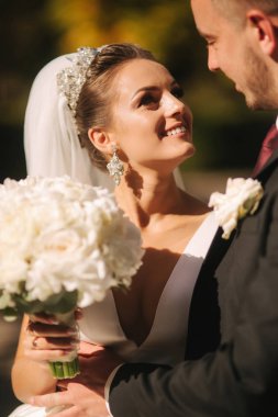 Güzel gelin kocası parkta. Sarı ağacın yanında yürüyorlar. Güzel makyaj