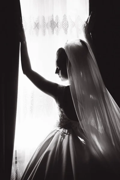 Silhouette di bella sposa a casa. Donna in piedi vicino alla finestra in abito da sposa. Bianco e nero — Foto Stock
