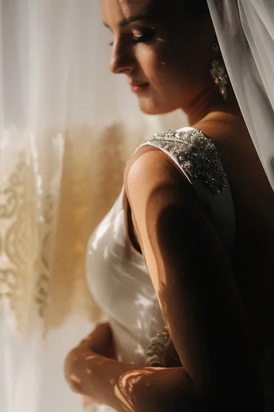 Ritratto di bella sposa a casa. Donna stare vicino alla finestra in abito da sposa — Foto Stock