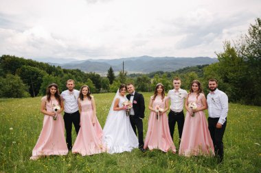 Damat ve gelin sağdıç ve nedime ile stand. Arkadaş grubu öpüşme yeni evliler. Düğün günü. Mountsins arka plan