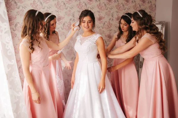 Gridesmaids helpen bruid haar thuis. Ochtend van beaufiful bruid. Meisjes hepl bruid kijken prachtig — Stockfoto