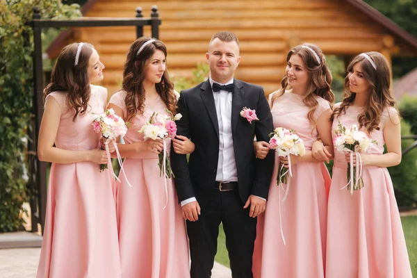 Красивый жених стоит рядом с красивой подружкой невесты с букетами — стоковое фото