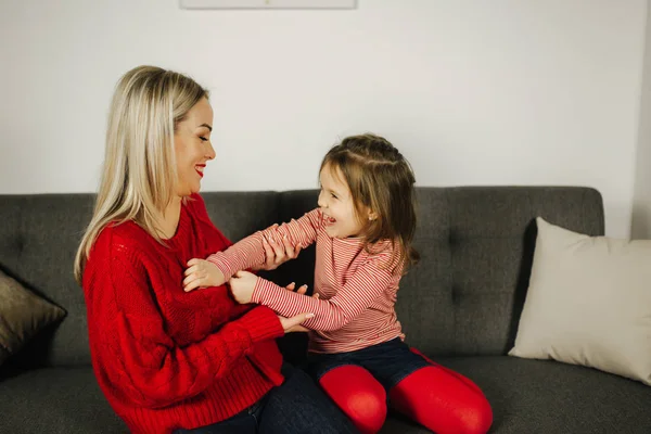 Mom and daughter play at home. Little girl tickle her mother. Happy family spend time together. Blond hair woman