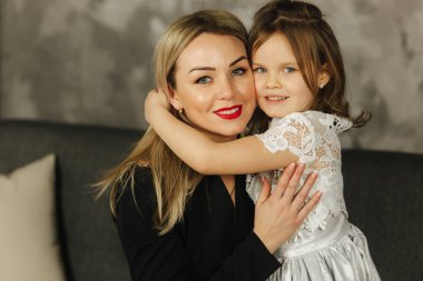 Küçük kız sarılmak anne ve gülümseme. Mutlu genç anne ile kızını evde