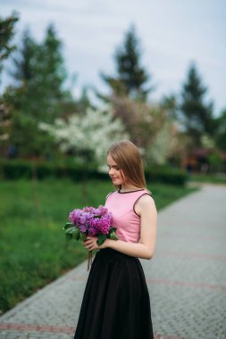 Çekici sarı saçlı kız tutuşsun leylak bir buket. Dışarıda sevimli kız
