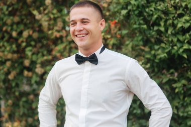 Parkta yürüyen genç adam. Whitr gömlekli yakışıklı damat