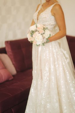 Güzel düğün elbisesi ile buket evde içinde zarif gelin. Sarı saçlı kadın güzel makyaj ve saç modeli ile