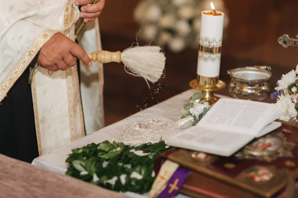 Kapłan uświęca obrączki. Tabela w kościele — Zdjęcie stockowe