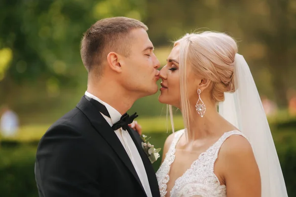 O noivo beija a noiva no nariz. Retrato de recém-casados fora — Fotografia de Stock