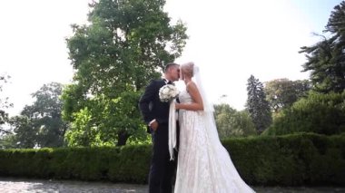 Parkta yürüyüş güzel düğün çifti. Beyaz uzun elbise ve şık damat ile gelin